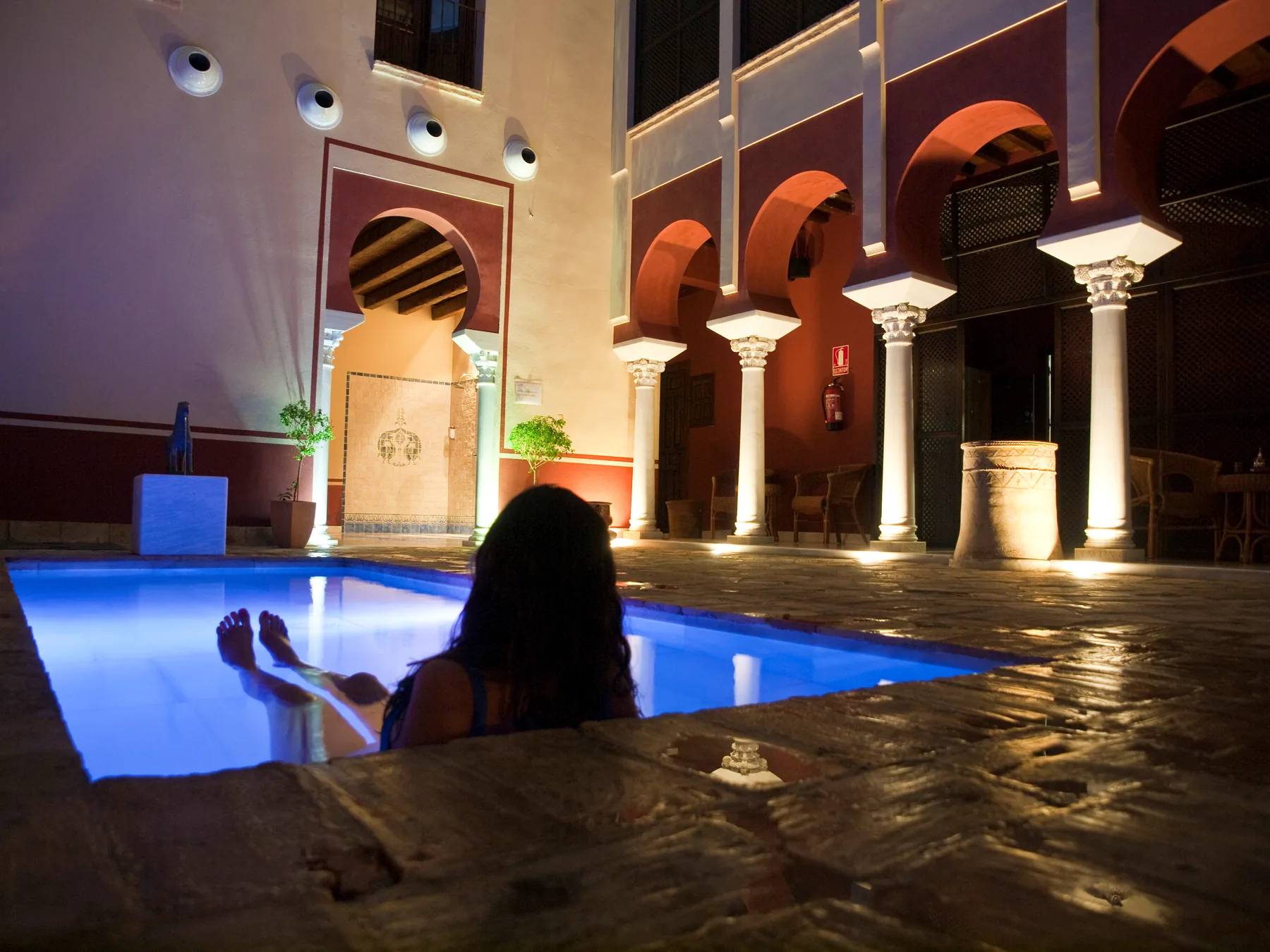 Mujer flotando en piscina del patio principal con columnata